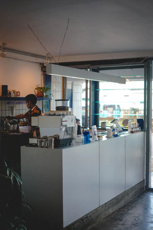 A barista preparing coffee behind a sunlit café counter