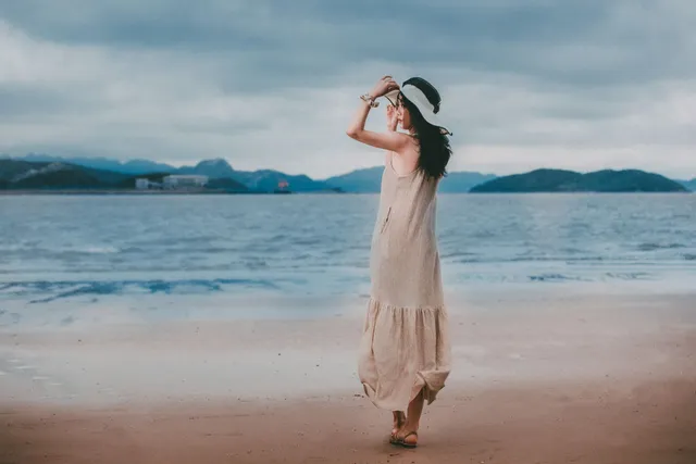 A woman in a summer dress walking beside the sea